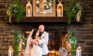 Bride and groom by the lit fireplace.