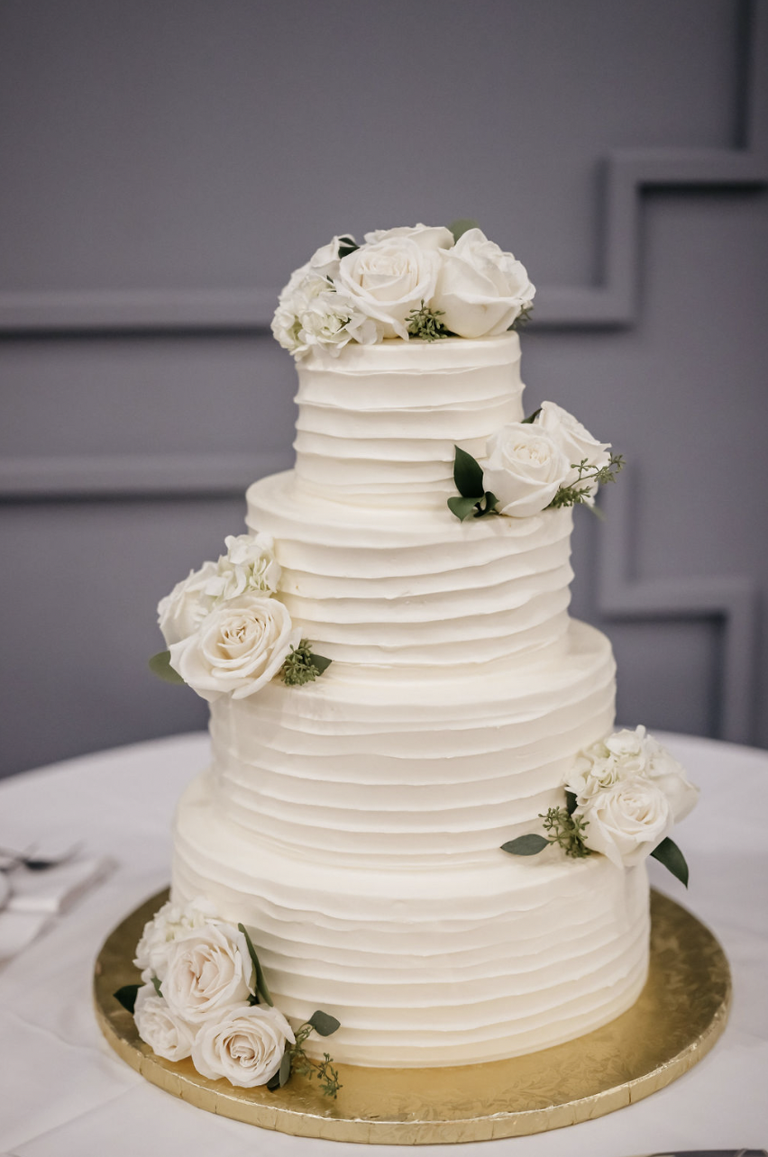 4-layered white cake with white roses.