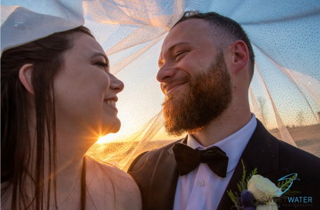 Bride and groom under the veil at sunset.
