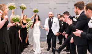 Bride and groom walk the aisle while the wedding party cheers.